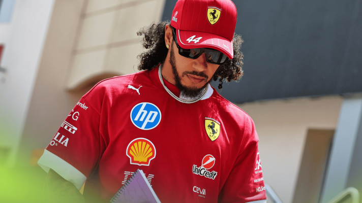 Lewis Hamilton with long hair as he clutches a notebook while making his way through the paddock in Bahrain