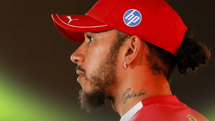 Lewis Hamilton wearing Ferrari team kit as he looks on in the Jeddah paddock