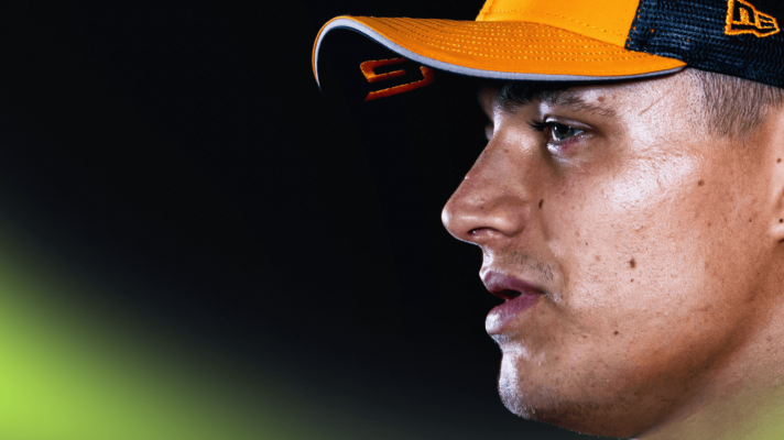 A side-profile close-up shot of Lando Norris looking emotional against a dark background