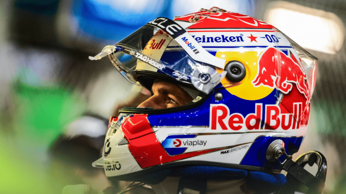 A close-up shot of Max Verstappen wearing his helmet with his visor open