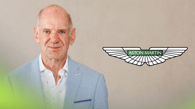 Adrian Newey wearing a suit on his first official image as an Aston Martin signing with a prominent Aston Martin logo alongside him
