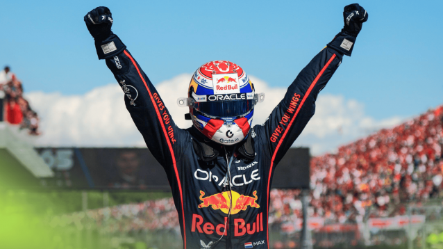 Max Verstappen raises both fists in celebration in parc ferme at Imola with a blue sky in the backdrop