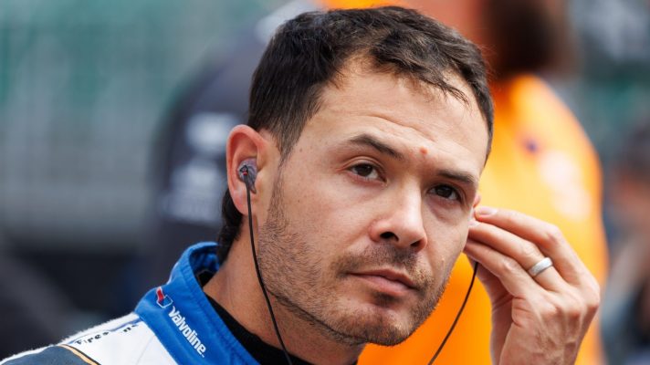 Kyle Larson in team overalls prepares to climb into his race car.