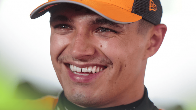 A close-up shot of Lando Norris smiling broadly