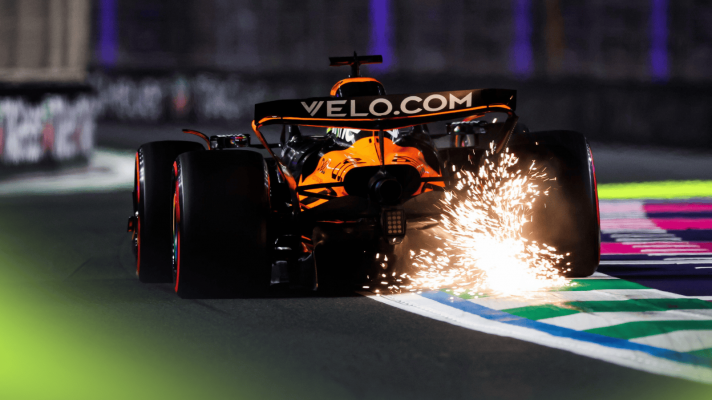 A rear-facing shot of Oscar Piastri's McLaren kicking up a shower of sparks over a kerb in Jeddah