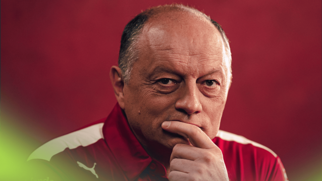 A studio shot of Fred Vasseur holding his hand to his mouth against a red background