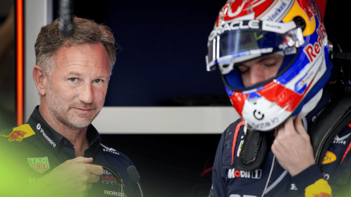 Christian Horner eyes the camera as Max Verstappen puts on his helmet in the Red Bull garage