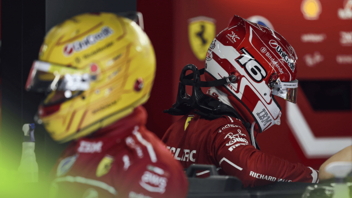 Lewis Hamilton and Charles Leclerc wearing their helmets in the Ferrari garage