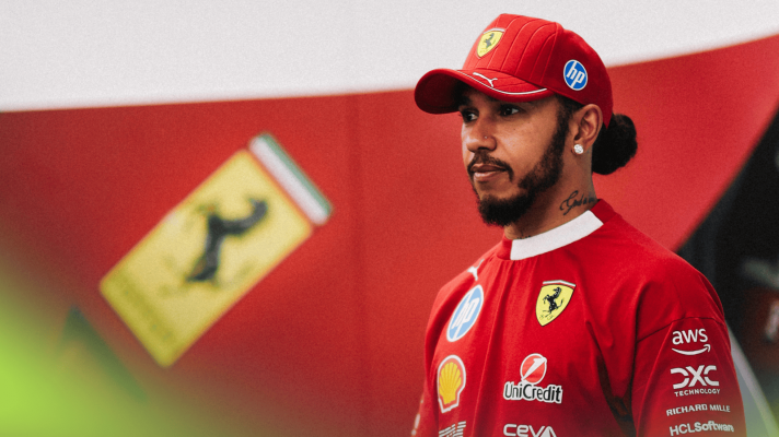 Lewis Hamilton looks on in Ferrari's hospitality unit with a giant Ferrari logo in the background