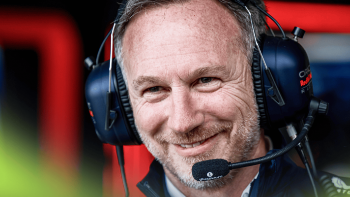 Christian Horner smiles while wearing a set of Red Bull-branded headphones