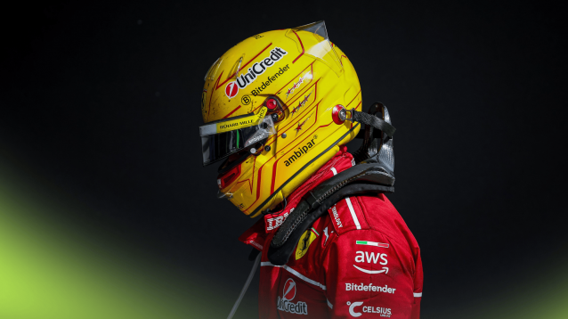 Lewis Hamilton walks with his head lowered while wearing his Ferrari race gear