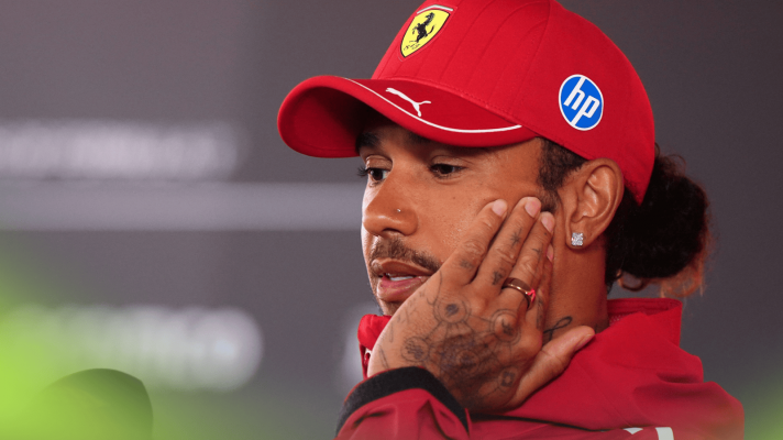 Lewis Hamilton holds his hand to his face as he speaks to the media