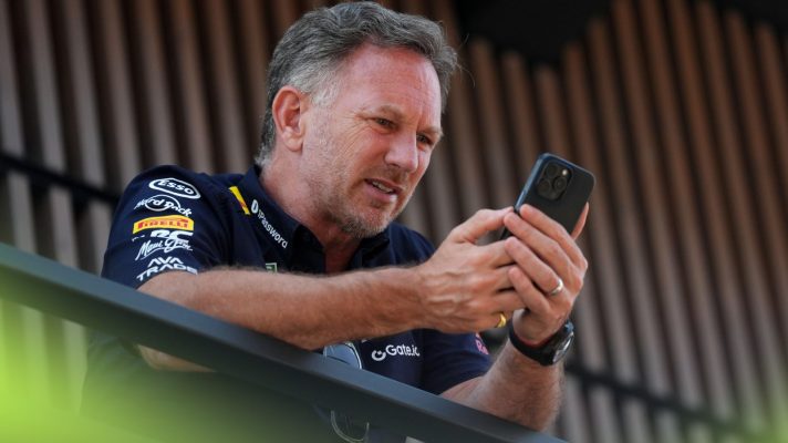 Former Red Bull team boss Christian Horner looks at his phone at the 2025 Spanish Grand Prix