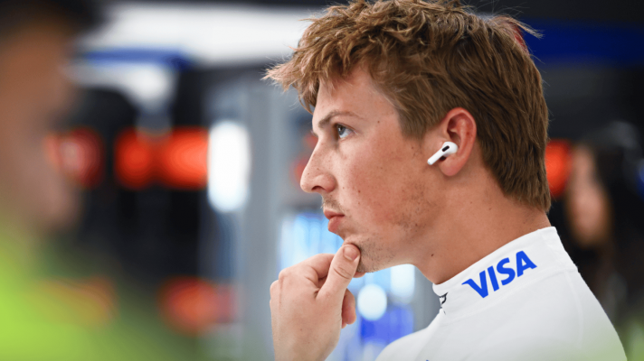 Liam Lawson holds his hand to his chin in the Racing Bulls garage
