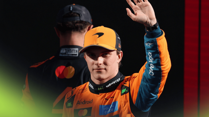 Oscar Piastri waving with Lando Norris walking away in the background