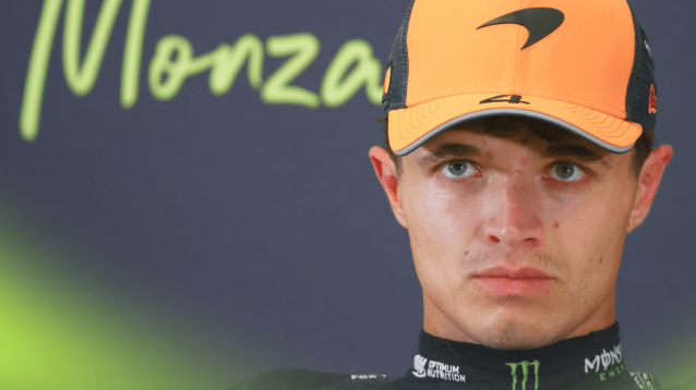 Lando Norris in a press conference with 'Monza' written on the wall behind him