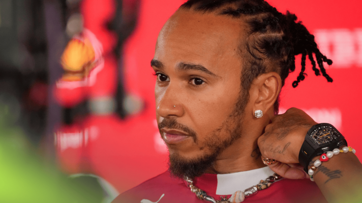 Lewis Hamilton touches his neck as he faces the media
