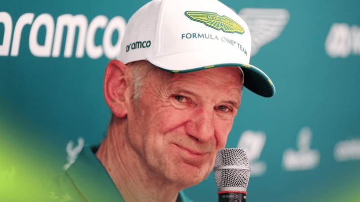 Adrian Newey smiles while holding a microphone during an Aston Martin press briefing