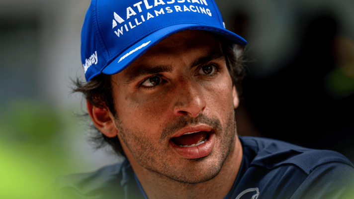 Carlos Sainz looks angry in conversation in the paddock