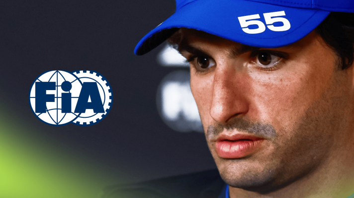 A close-up shot of Carlos Sainz looking downcast in a press conference with a prominent FIA logo alongside him