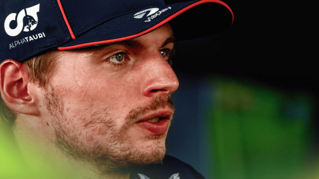 A close-up shot of Max Verstappen looking strained as he faces the media