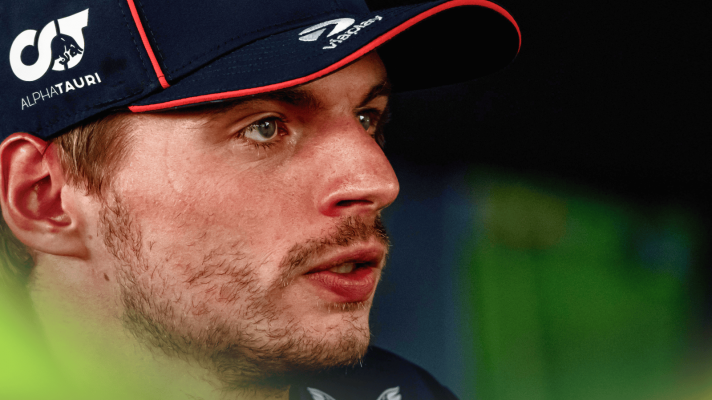 A close-up shot of Max Verstappen looking strained as he faces the media