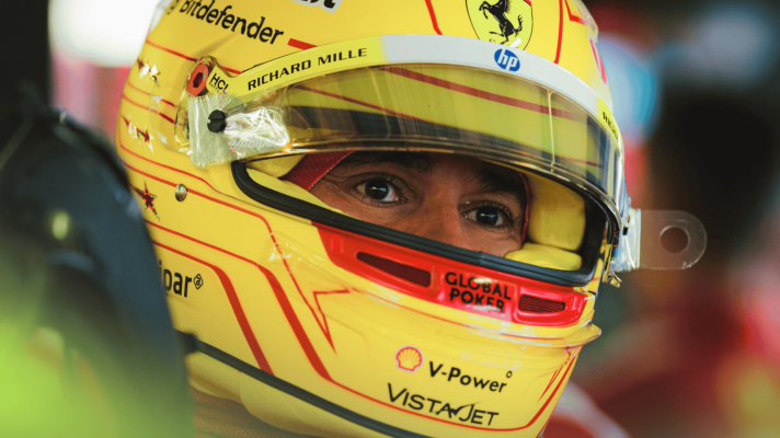Lewis Hamilton's eyes visible through the open visor of his yellow Ferrari helmet