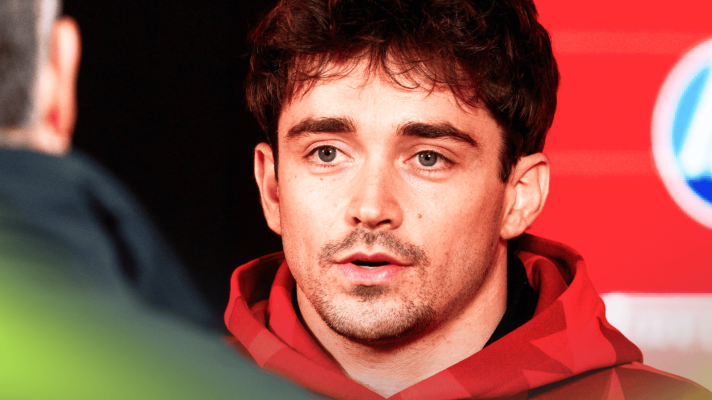 Charles Leclerc speaking to the media while wearing a red Ferrari hoodie