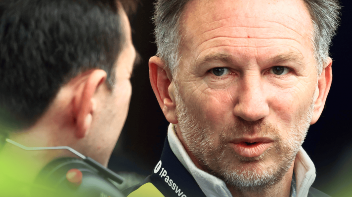 A close-up shot of Christian Horner in conversation with a Red Bull engineer in the garage