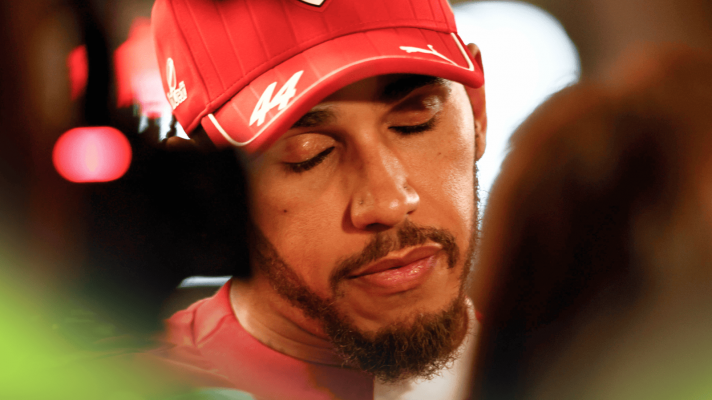 A close-up shot of Lewis Hamilton closing his eyes as he faces the media