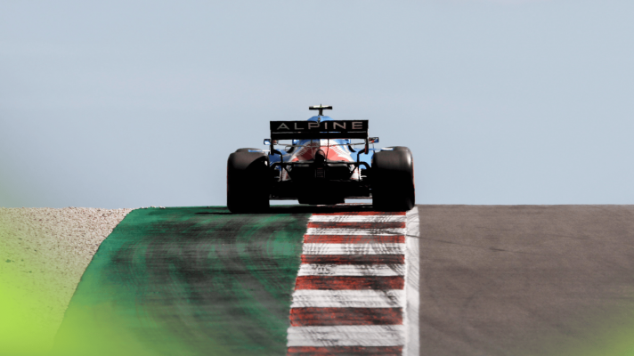 A rear-facing shot of Fernando Alonso's Alpine rising up a hill in Portimao with blue sky in the background
