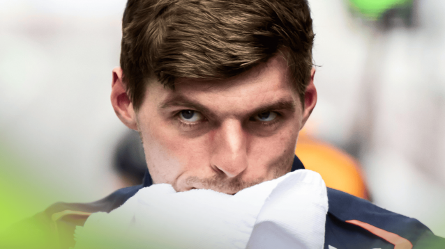 Max Verstappen looks on angrily as he wipes his face with a towel