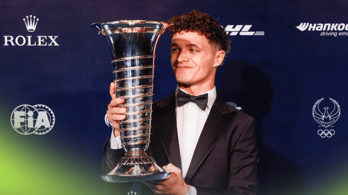 Lando Norris smiles as he holds the F1 world championship trophy aloft