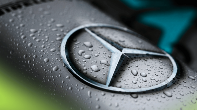 An extreme-close up shot of raindrops following on the nose of a Mercedes F1 car with the brand's logo visible