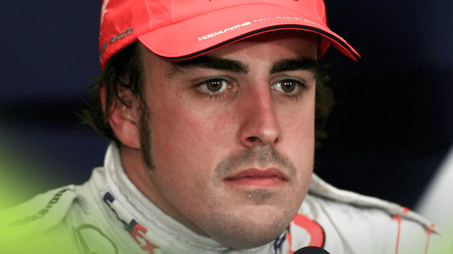 A close-up shot of Fernando Alonso wearing McLaren overalls and a cap in a 2007 press conference