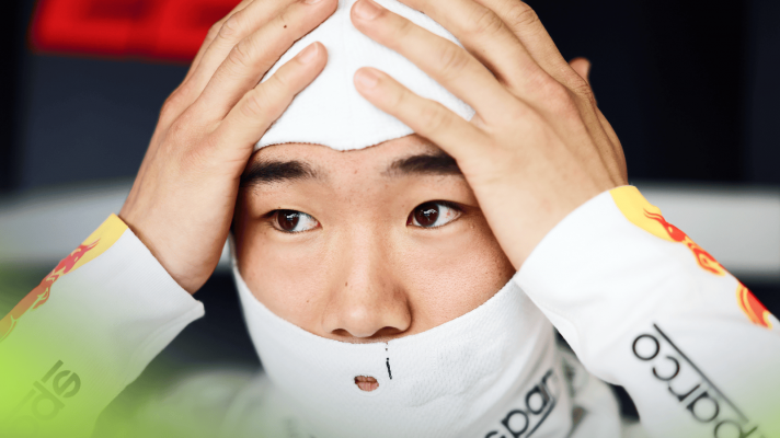 Yuki Tsunoda holds his hands to his head as he puts on his balaclava