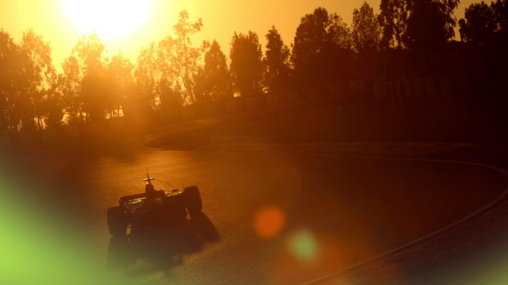 A rear-view shot of an F1 car on track in Barcelona as the sun sets