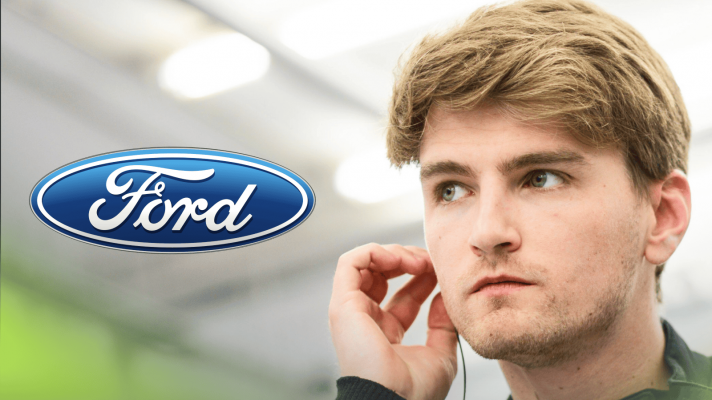 Logan Sargeant inserts his earplugs in the garage with a prominent Ford logo alongside him