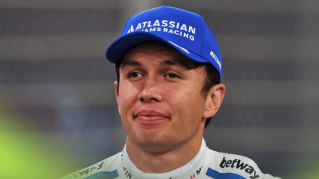 Alex Albon smiles thinly while wearing a blue cap during Williams' end-of-season photocall in Abu Dhabi