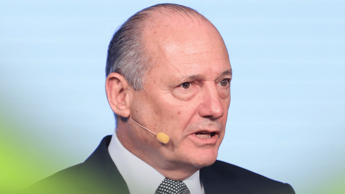 A close-up shot of Ron Dennis speaking into a microphone attached to his ear at a 2015 press conference
