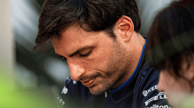 Carlos Sainz sits looking downcast with his head lowered