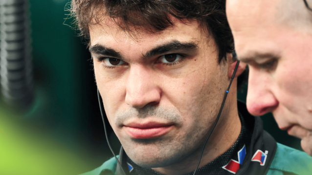 A close-up shot of Lance Stroll looking on in the Aston Martin garage