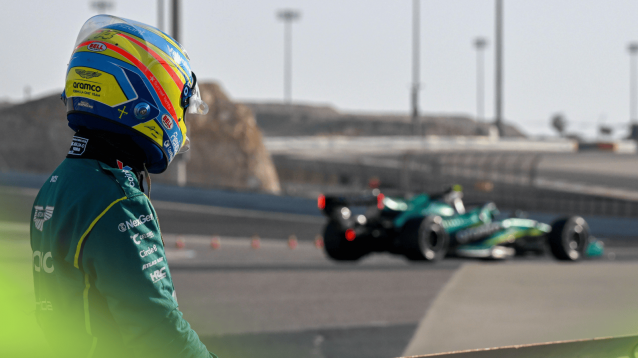 Fernando Alonso looks on with his stricken Aston Martin AMR26 in the background in Bahrain