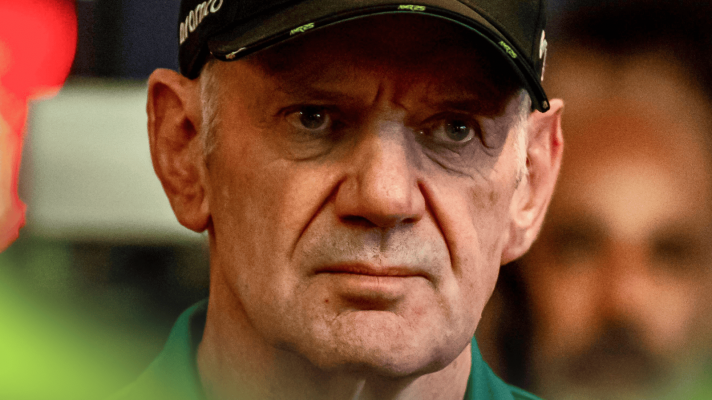 A close-up shot of Adrian Newey wearing an Aston Martin cap in the paddock