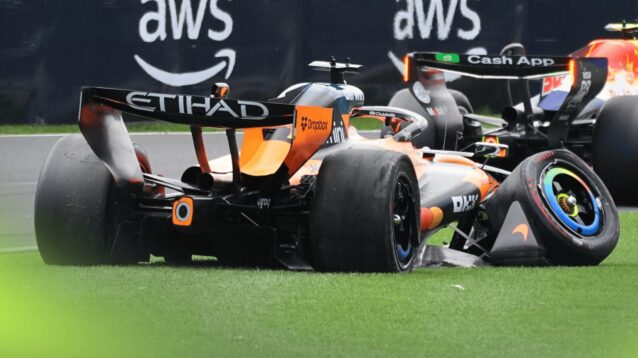 A rear-view shot of Oscar Piastri's McLaren on the grass with severe damage