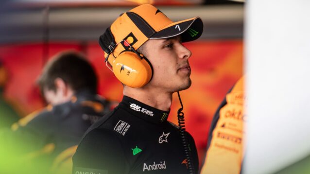 Lando Norris wears a headset in the McLaren garage.