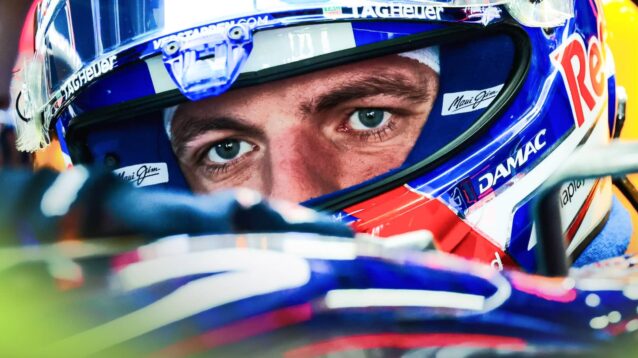 Max Verstappen's eyes visible through the open visor of his helmet as he sits in the Red Bull RB22