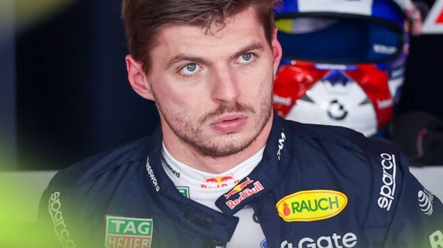 Max Verstappen looks on in the Red Bull garage with his crash helmet on a shelf in the background