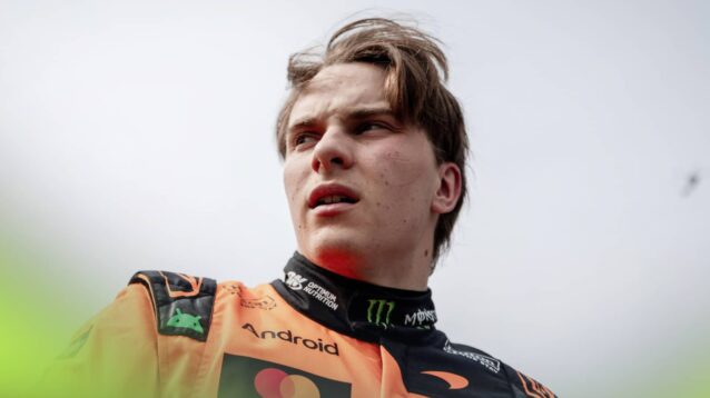 Oscar Piastri pictured from a low angle with a grey sky in the background