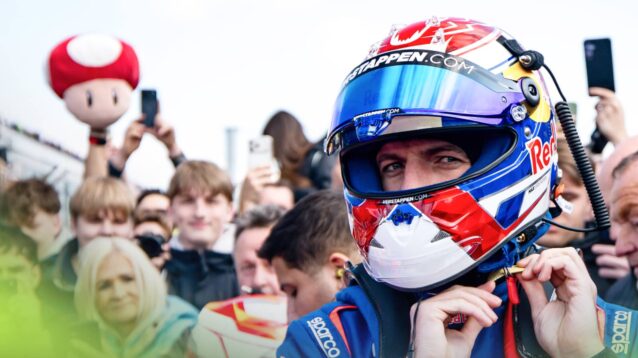 Max Verstappen fastens his helmet on the grid at the Nurburgring with someone in the crowd waving a Super Mario mushroom toy